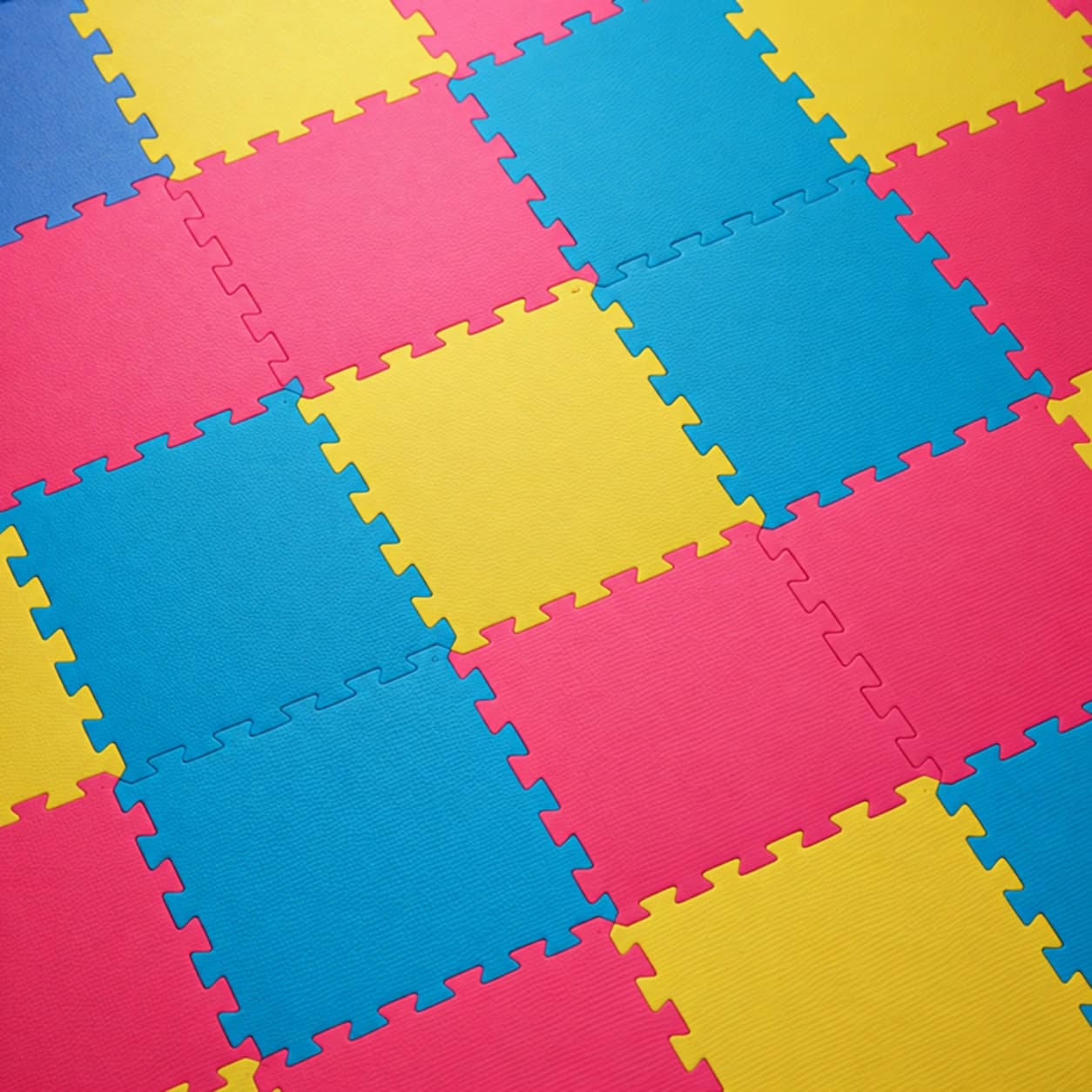 Tatames EVA coloridos em azul, rosa e amarelo com encaixe tipo quebra-cabeça